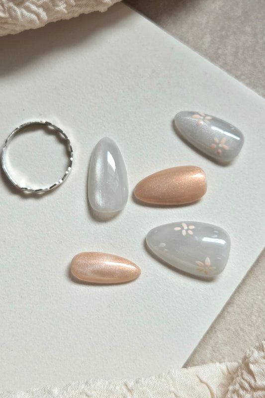Soft grey-blue press-on nails with champagne shimmer and delicate hand-painted florals. Handmade, reusable and available in your choice of shape and size.