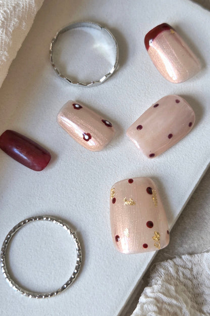 Merlot Kiss champagne and wine-red hand-painted press-on nails with floral and gold foil details