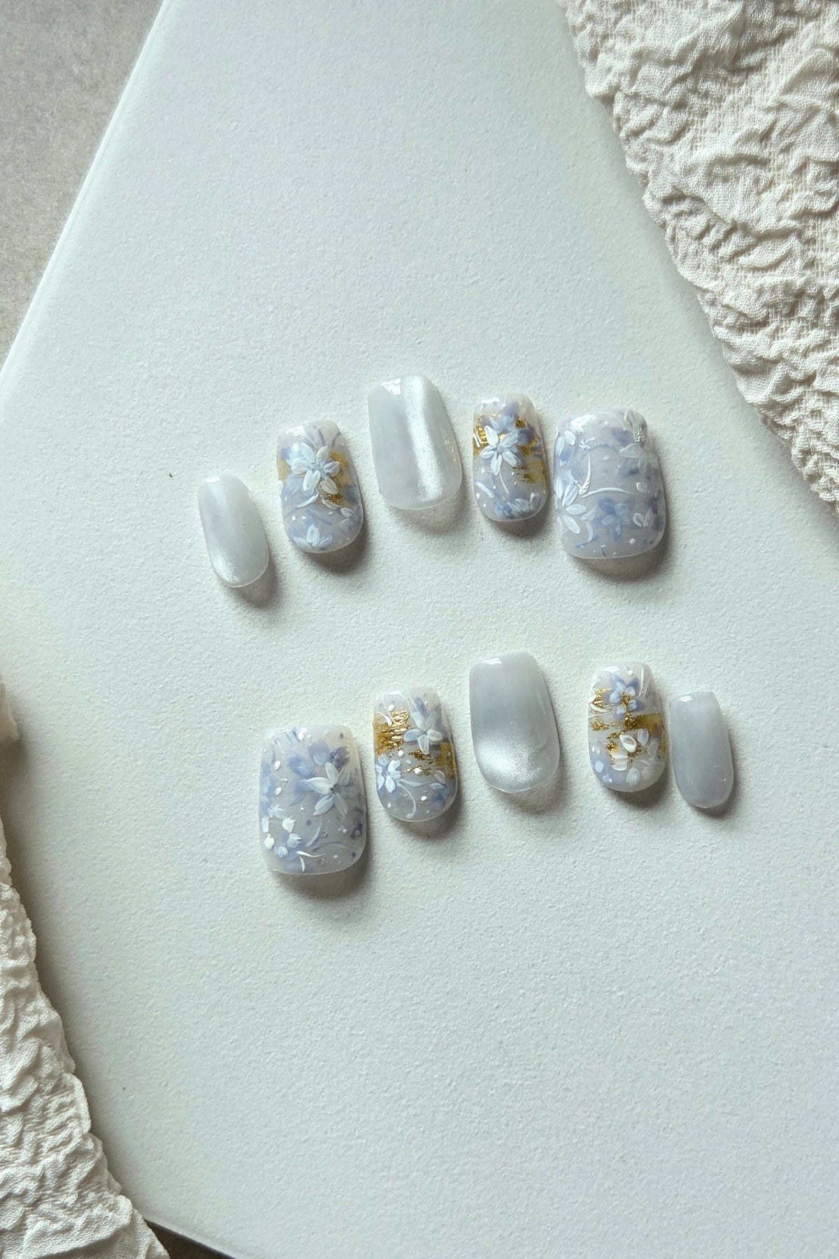 Blue Whisper blue and pearly white hand-painted press-on nails with floral and gold foil details