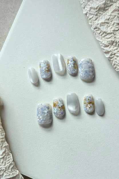 Blue Whisper blue and pearly white hand-painted press-on nails with floral and gold foil details