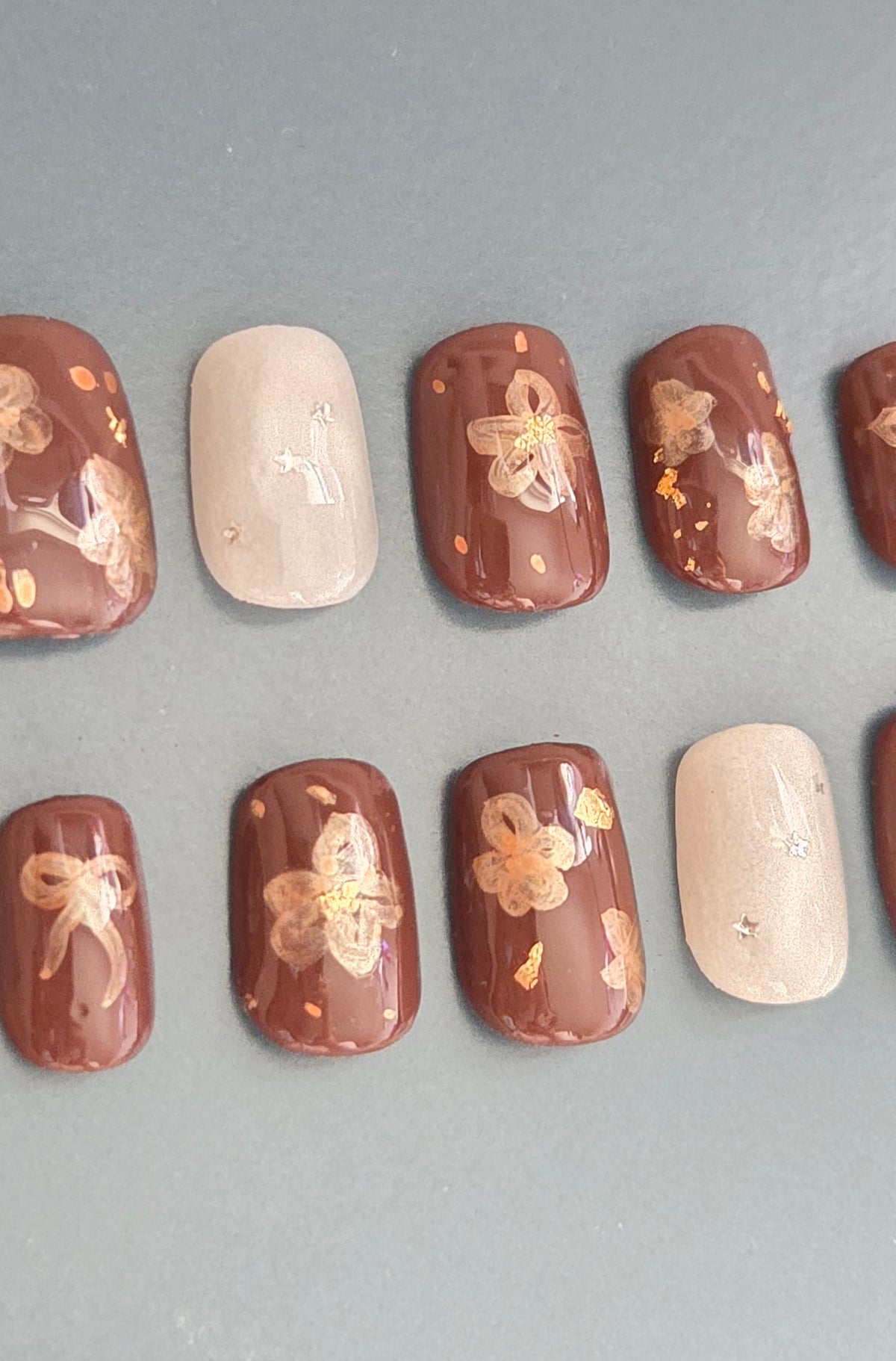 Cinnamon Blossom hand-painted brown floral press-on nails with ribbon details and nude accent nails
