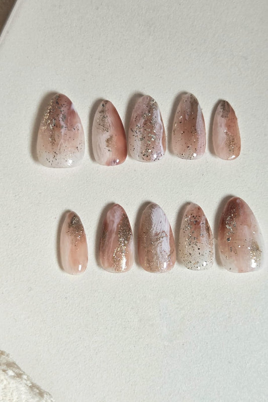 Blush nude press-on nails with milky marble details, gold foil and subtle shimmer. Handmade, reusable and available in your choice of shape and size.