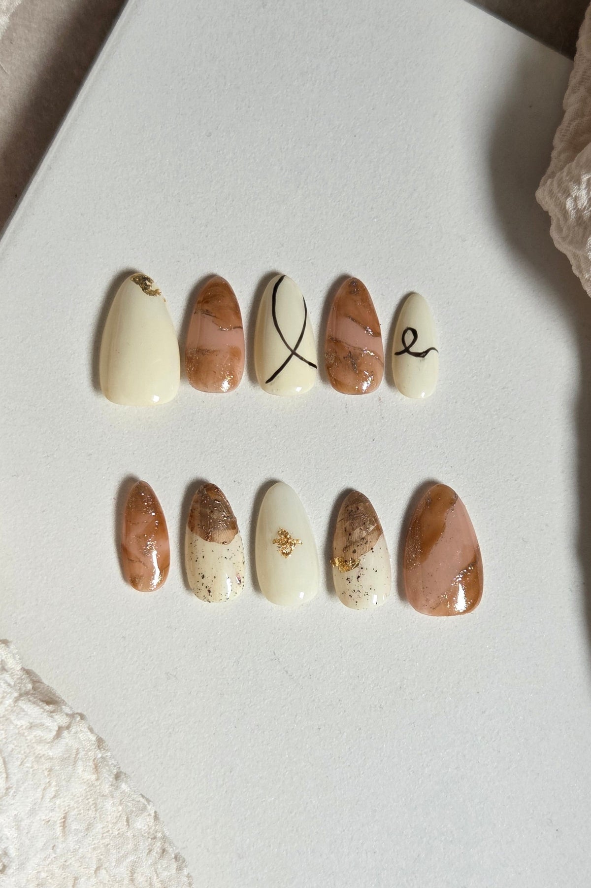 Cream, amber and nude press-on nails with gold foil and abstract line details. Handmade, reusable and available in your choice of shape and size.
