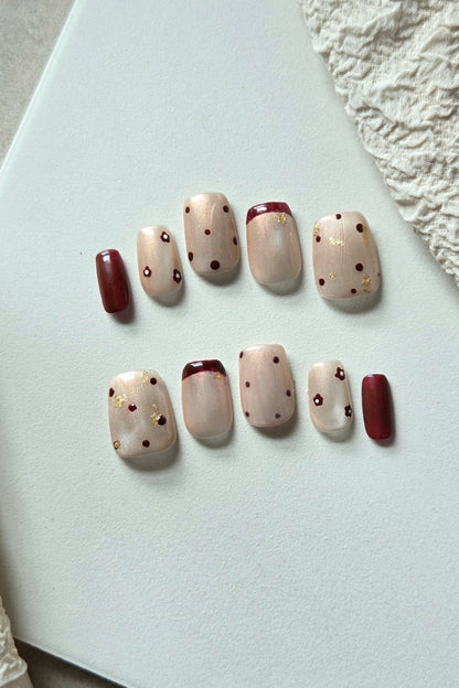 Merlot Kiss champagne and wine-red hand-painted press-on nails with floral and gold foil details