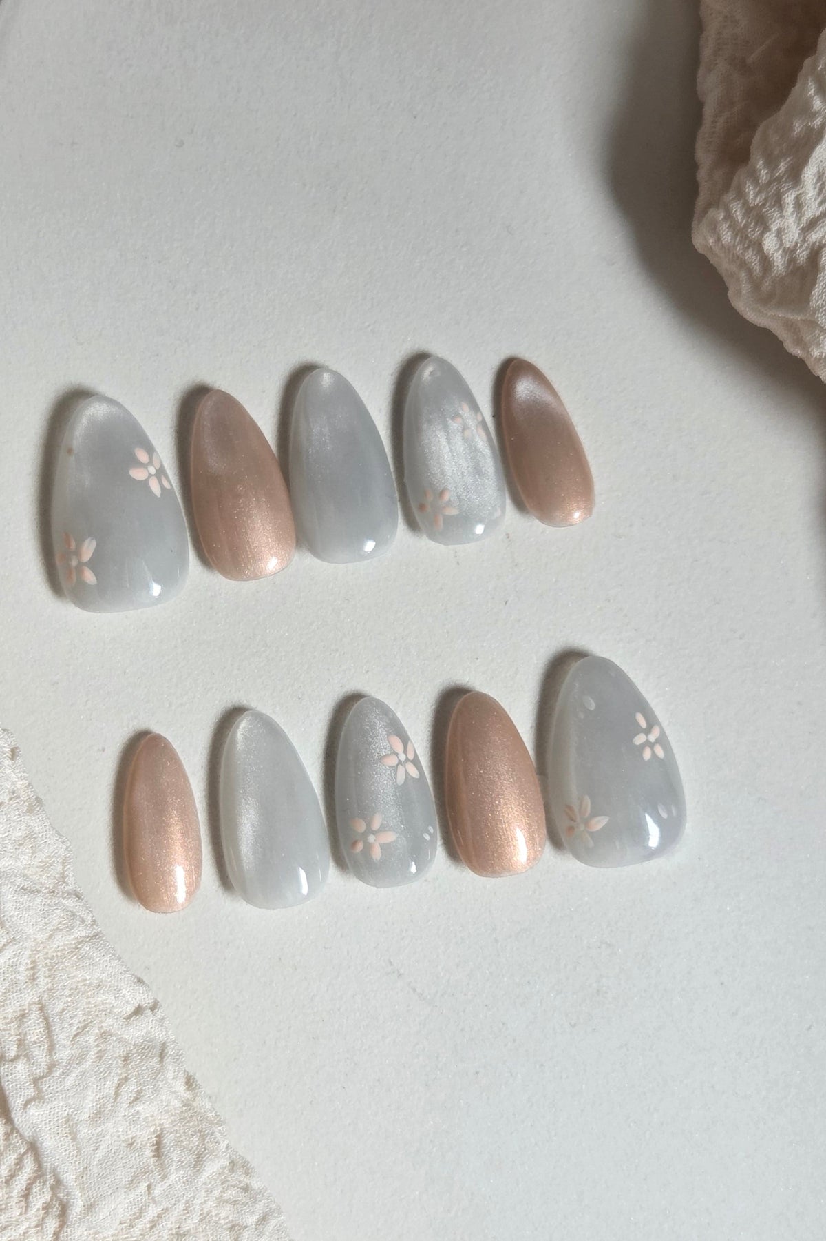 Soft grey-blue press-on nails with champagne shimmer and delicate hand-painted florals. Handmade, reusable and available in your choice of shape and size.